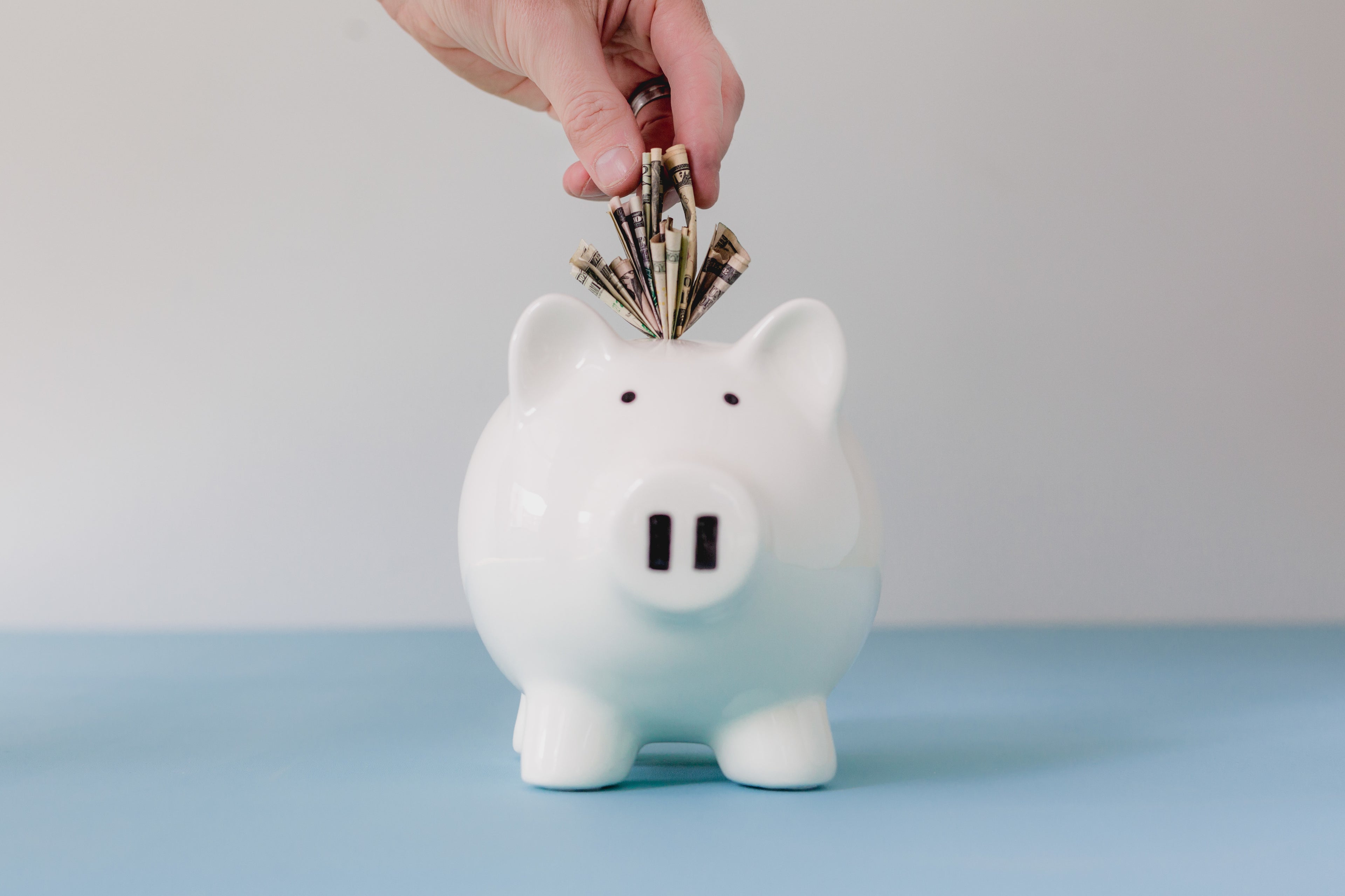 Hand putting money in piggy bank
